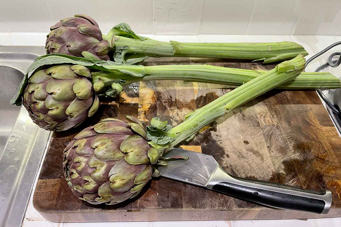 Preparo il condimento. Pulisco i carciofi eliminando le foglie esterne più dure, e man mano li metto in una ciotola con acqua fredda e limone affinchè non si anneriscano.