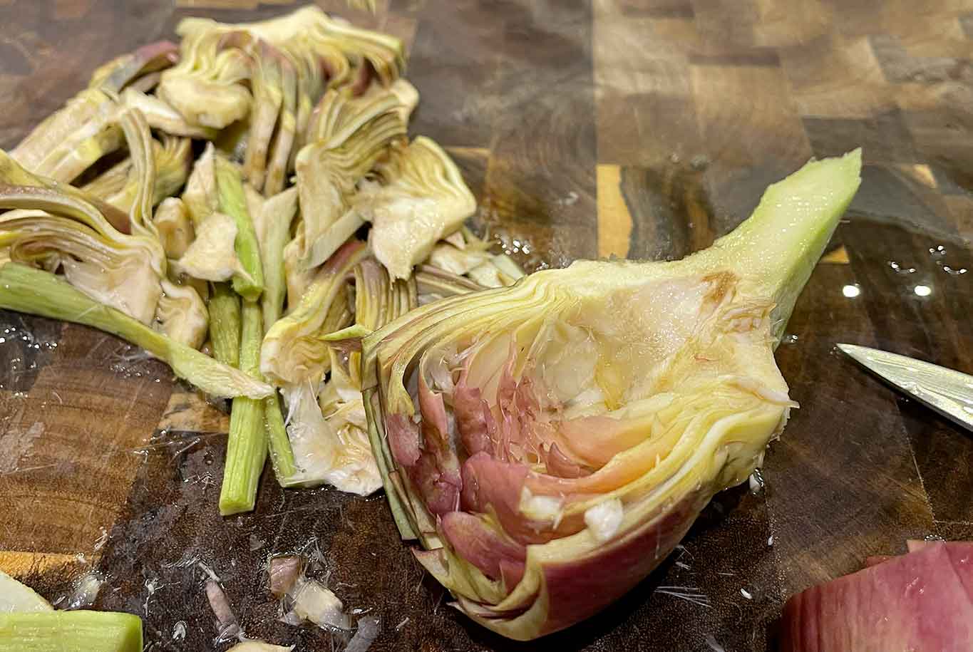 Riprendo il carciofo, taglio l’estremità di netto, pulisco il gambo e lo taglio a metà. Elimino la barbetta e lo taglio a strisce sottili in altezza.