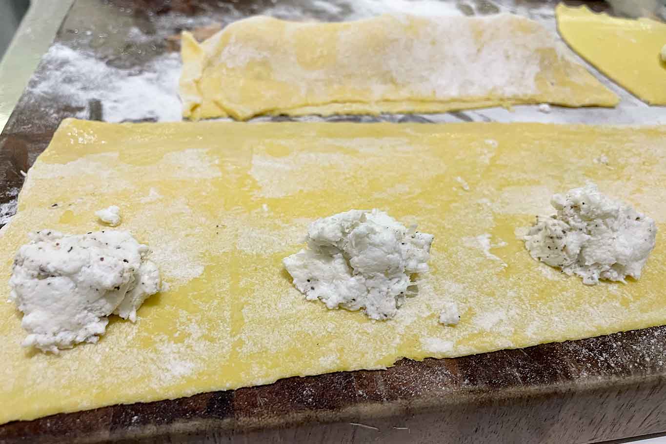 Dispongo il ripieno con un cucchiaino circa a metà della sfoglia e così via procedo in orizzontale lasciano un po’ di margine all’esterno. Prima di richiudere l’impasto su se stesso, bagno leggermente con un pochino di acqua le estremità per far sì che il raviolo non si apra in cottura.